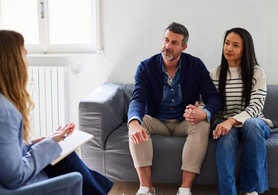 Female psychologist guiding and assisting mid adult couple in resolving marriage issues during counseling session